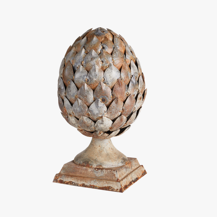Decorative artichoke sculpture on a pedestal with a white background